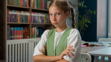 Üzgün yorgun Kafkasyalı küçük kız çocuğu öğrenci öğrenci ilkokul öğrencisi kollarını kavuşturup kameraya bakan ev içi suç öğrenme problemleri cezasından korkan öğrenci.