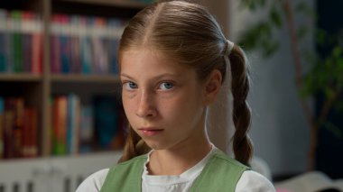 Üzgün, küçük, beyaz, liseli, depresyondaki öğrenci, mutsuz, öğrencilerden sıkılmış, kameraya bakıyor, sorunları inceliyor, eğitim zorbalığı, kapalı kütüphane sınıfında sorun öğreniyor.