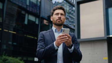 Kafkasyalı bir adam akıllı telefon erkek girişimci kullanıyor. Şehir iş adamlarının internet bağlantılarını kuruyor. Dışarıdaki internet üzerinden mesaj yazıyor.