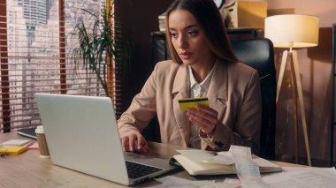 Odaklanmış profesyonel Kafkas kız iş kadını kadın girişimci patron ofis çalışanı çevrimiçi kredi kartı işlemleri için ödeme yapan ev içi bilgisayar şifreli veri yazma