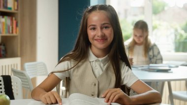 Sevimli küçük çocuk öğrenci kitap okuyor, kitap okuyor, ilkokul öğrencisi, ilkokul öğrencisi, çocuk okuyor, ders kitabı okuyor, neşeli, mutlu, gülümseyen liseli kız derslerine hazırlanıyor.