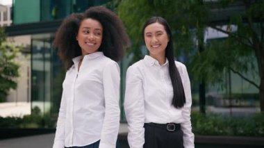 İki Afro-Amerikalı, Asyalı, Çinli kadın, iş kadını iş ortağı iş ortağı iş ortağı, iş arkadaşı, takım olarak gülümseyen, çok ırklı, açık havada poz veren kızlar.