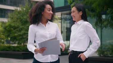 İki farklı kadın tartışma projesi hakkında konuşuyor. Afrikalı Asyalı kadın iş kadını açık havada iş kadını başarısı. Mutlu iş arkadaşları takımı kazananları kutluyor.