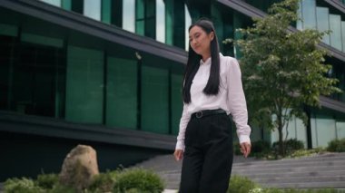 Başarılı bir Asyalı, kendine güvenen Koreli kadın, iş kadını, merdivenlerden yukarı çıkıyor, şehir merkezine iniyor, çalışan, girişimci, gülümseyen lider, Ceo merdiven ofis merkezinin önünde yürüyor.