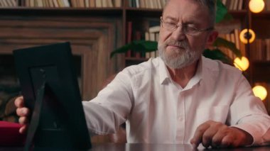 Elinde fotoğraf çerçevesi fotoğrafı tutan yaşlı beyaz adam hatırlar erkek işadamı nostaljisi kapalı ofis nostaljisi yaşlı büyükbaba gözlüğünü çıkarır sağlık öngörüsü görme