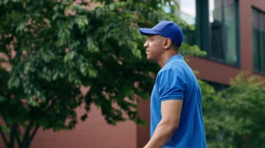 Gülümseyen mutlu portre kaygısız Afrikalı Amerikalı teslimatçı erkek kurye elinde kağıt torba yiyecek teslimatı paketleme dükkânı paketleme dükkânı alışverişi kameralara bakarak