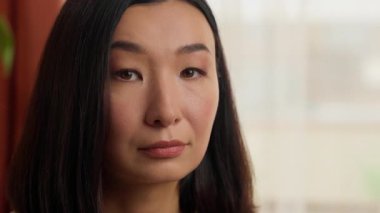 Ciddi ciddi düşünceli Asyalı Çinli kadın kameraman kız iş kadını, etnik eş ev hanımı ev sahibi ev sahibi kiracı vesikalık işine bakıyor.