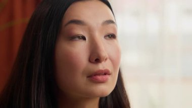 Yüzünüzü kapatın. Düşünceli, düşünceli, Asyalı bir kadın. Kadın ev kadını, hayal kuruyor.