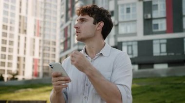 Kafası karışmış Kafkasyalı bir adam cep telefonu akıllı telefon konumu kullanıyor turist erkek işadamı iş şehrini araştırıyor şaşkın bir adam açık havada navigasyon kayboldu şehir uygulaması GPS navigatörü