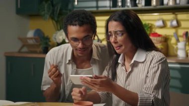 Afrikalı Amerikalı erkek Arap kız, çok ırklı kadın arkadaş, mutlu öğrenci çift, ev-mutfak cep telefonu iyi haber, çığlıklar, akıllı telefon yarışı, online bahis.