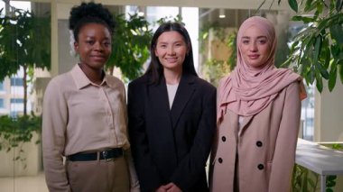 Gülümseyen iş kadınları, çok ırklı Afrikalı Asya Müslüman çeşitliliği kız iş arkadaşları, iş arkadaşları birlikte hareket ediyor.