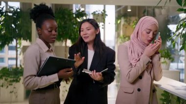 Çeşitli mutlu çok ırklı iş ortakları Afrikalı Müslüman iş kadınları gülen kızlar ofiste iş arkadaşlarıyla sohbet ediyorlar sohbet ediyorlar telefon konuşmaları yapan kadınlar ortaklığı