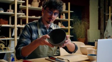 Sanat çömlekçisi heykeltraş adam el yapımı el işi el işi el işi çanağı satışı seramik erkek pazarlamacı küçük işletme sahibi dizüstü bilgisayarda alışveriş malzemeleri yazıyor.