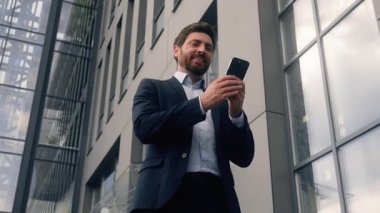 Şirketin yanında yürüyen girişimci işe giderken cep telefonuyla sohbet eden akıllı telefon uygulama aleti bağımlısı Kafkasyalı yönetici Avrupalı iş adamı erkek iş adamı