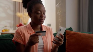Mutlu, Afrikalı, etnik, Amerikalı, bayan, ev sahibi, iş kadını, elinde kredi kartı olan, cep telefonu, akıllı telefon kullanan, online ekommerce siparişi veren, ev koltuğu teslimatı yapan kadın.