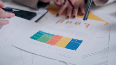 Tanımlanamayan çok ırklı kadın takım kızları, iş arkadaşları, iş arkadaşları, kağıt döküman grafiği analizleri, kapalı ofis içi toplantı odası stratejisi tartışmaları.