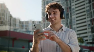 Neşeli, Avrupalı Avrupalı, müzik kulaklığı dinleyen, kulaklık takan, cep telefonlu, akıllı telefon kullanan, erkek, şarkı listesindeki, müzik listesindeki, açık hava işadamını dinleyen neşeli Avrupalı öğrenci.