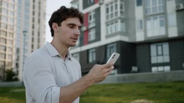 Konsantre Kafkas Avrupalı adam adımlarını atıyor cep telefonu iş adamı olarak yürüyor şehir sokaklarında erkek işadamı gülümseyen sohbet aleti teknolojisi düşünüyor.