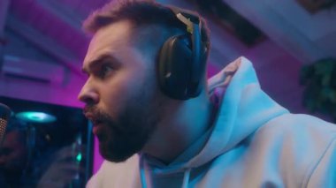 Odaklanmış Kafkasyalı flamalı sunucu erkek oyuncu vlogger sanal oyundan zevk alıyor modern erkek sosyal medya siber sporu ev etkili blog bağımlısı blogger çevrimiçi bilgisayar neonu oynuyor