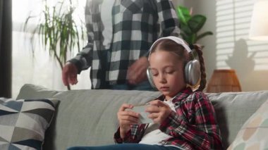 Evde beyaz bir aile var. Meşgul küçük kız çocuk kız çocuk, gadget bağımlısı cep telefonu akıllı telefon video oyunu kulaklıklarıyla bağıran öfkeli anne kadını görmezden geliyorlar.