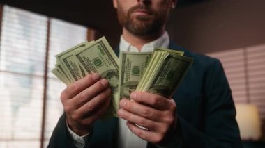 Ciddi ciddi Kafkasyalı yetişkin işadamının elinde yığınla para var. Kapalı mekanda finansman sayıyor. Maaş paraları sayıyor.