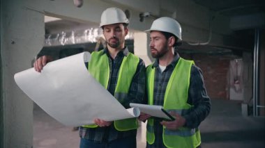 Kafkasyalı iki adam mimar erkek mühendis erkek miğfer erkek miğfer ve yelek inşa planı projesini planlayan kağıt işçileri müteahhitleri konuşan belgesel müteahhitleri