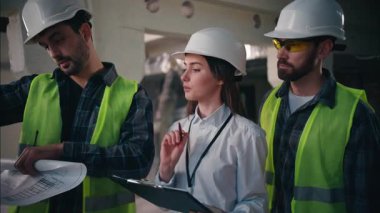 Profesyonel Kafkasyalı inşaat işçileri planlama işinde çalışan erkekler planlamacı işçiler taslak detaylarını tartışan işçiler kadın müteahhitler fabrika inşaatçılarının evrak işleri planlıyorlar.