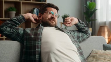 Gülümseyen, gevşeen, dinlenen, beyaz erkek, ev sahibi kanepede dinlenen, ev kredisi esneyen, uykulu, uykulu, uykulu, uykusuz, uykusuz, uykusuz, uykusuz, uykusuz bir adam.