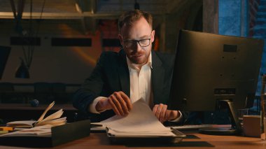 Yorgunluktan bitap düşmüş, geç saatlere kadar çalışan sıkıcı iş adamı çok çalışan Kafkasyalı işadamı işvereni kontrol et kağıtları kontrol et bilgisayarlı adam, erkek adam karanlık gece ofisinde fazla mesai yapıyor.