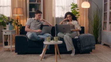 Çok ırklı çift aletleri bağımlısı aile bilgisayarları bağımlısı, beyaz erkek, dizüstü bilgisayar kullanıyor, Latin kadın, daktilo yazan, serbest çalışan, ev bilgisayarları ile meşgul.