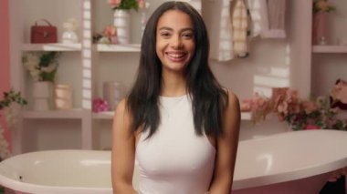 Gülümseyen mutlu bir kız pembe şeker banyosu içinde mutlu İspanyol kadın ev kameraya bakıyor gülümsüyor baş parmak işareti olumlu işaret mükemmel güzellik cilt bakımı iyi tavsiye