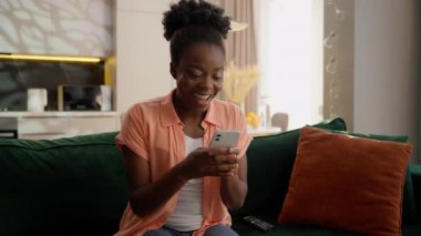 Heyecanlı Afrikalı Amerikalı iş kadını etnik kız iş kadını cep telefonu sahibi akıllı telefon zaferi kutluyor çevrimiçi oyun başarısı evde yumruk hareketi heyecanı