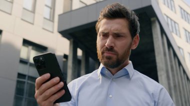 Ofisin yakınındaki üzgün, kaygılı erkek kötü haber okuyor. Reddedilmiş banka tebligatı sorunu var. Kafkasyalı iş adamı iş adamı şehirde cep telefonu kullanıyor.