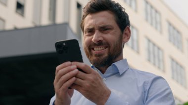 Sinirli, sinirli, sinirli, sinirli, beyaz, orta yaşlı iş adamı, iş adamı, iş adamı, şehirdeki iş adamı, cep telefonu uygulaması, akıllı telefon konuşmaları, akıllı telefon mesajı, iş yeri sorunu.