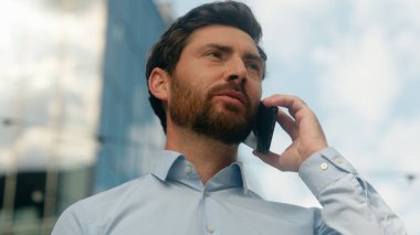 Kafkasyalı gülümseyen mutlu orta yaşlı iş adamı erkek işadamı. Güneşli bir şehirde iş adamı. Konuşan cep telefonu iletişimi akıllı telefon görüşmeleri.