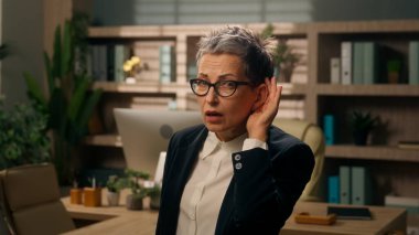 Ciddi bir beyaz iş kadını portresi. Yaşlı, yaşlı, olgun, emekli bayan işkadını. Kulağının dibinde el ele tutuşmuş.