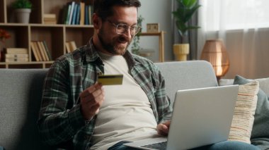 Mutlu gülümseyen müşteri alıcısı, kredi kartı ve dizüstü bilgisayarla alışveriş yapan beyaz erkek online satın alma çeki para hesabı, yemek teslimatı, internet hesabı.