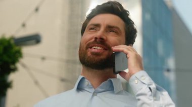 Kafkasyalı gülümseyen mutlu orta yaşlı iş adamı erkek işadamı. Güneşli bir şehirde iş adamı. Konuşan cep telefonu iletişimi akıllı telefon görüşmeleri.