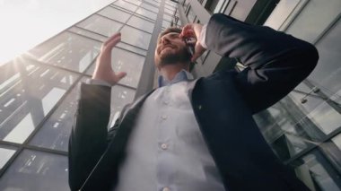 Alttaki görüntüde duygusal mutlu konuşma cep telefonu görüşmeleri şirket akıllı telefonu görüşmeleri Kafkasyalı orta yaşlı iş adamı yetişkin iş adamı erkek girişimci şehir ofisindeki güneş binası