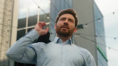 Beyaz tenli, güler yüzlü, rahat, rahat, orta yaşlı, iş adamı, güneşli şehirde girişimci erkek. Omuzlarına resmi bir ceket giyip moda modasına uygun bir son ver.