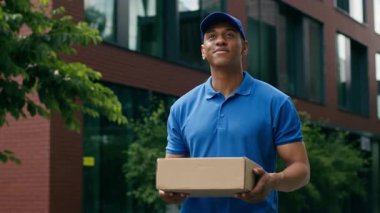 Olumlu gülümseyen Afro-Amerikan etnik kurye erkek postacı postayla alışveriş hizmeti taşıyan postacı postacı postası taşıyan postacı.