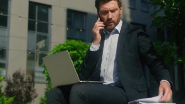 Kafkasyalı, orta yaşlı iş adamı, şehirde cep telefonuyla konuşan bir girişimci. Dizüstü bilgisayarla iş belgelerini kullanarak.