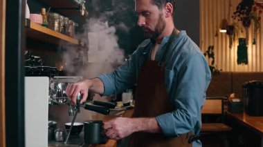 Yetişkin Kafkasyalı küçük işletme sahibi işçi garson garson garson adam kafeteryadaki yemek servisi yapan adam barmen kahve makinesi ekipmanına sıcak espresso dök kafe çalışanı içki yap.