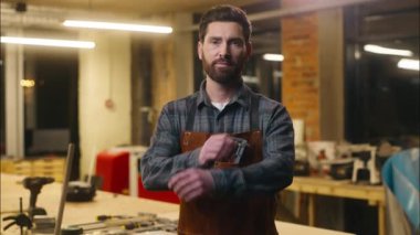 Gülümseyen Kafkas profesyonel marangoz yetişkin çalışan sanatçı neşeli erkek tamirci atölyede kamera sanatına bakan marangozluk ustası