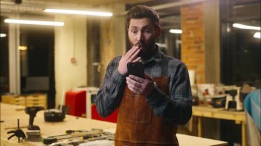 Şaşırmış Kafkasyalı ahşap ustası tamirci erkek parşömen tomarı cep telefonu sürprizi çevrimiçi tamircinin işçiye 