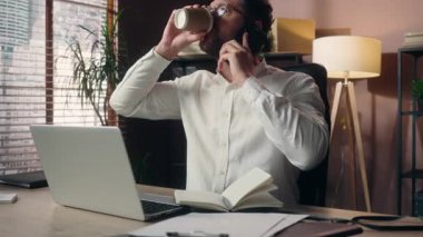 Çok çalışan Kafkasyalı yönetici erkek cep telefonu işadamı girişimci yönetici yazar. Yetişkin işadamının ofis çalışanlarının aşırı yüklemelerinde dizüstü bilgisayar kullandığını belirtiyor.