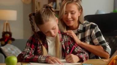 Portre neşeli beyaz kız ev ödevi yapıyor mutlu ebeveyn anne, kız öğrenci kız öğrenci eğitimi veriyor ev kadını anne çocuğu kamera eğitimi görevine bakıyor aile çocuk bakımı