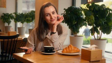 Gülümseyen mutlu kadın kafe ziyaretçi müşterisi kafeterya restoranında elinde cep telefonu, elinde yeşil ekran akıllı telefon görüntüsü, krom ekran menü siparişi gibi kameraya gülümse.