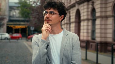 Düşünceli düşünme çözümü, düşünceli, düşünceli, kafası karışık bir iş adamının şehir dışında gülümseyen kameraya bakarak bir fikir üretmesine karar verdi.