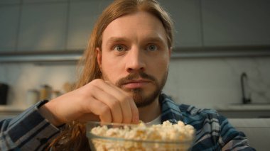 Odaklanmış beyaz erkek, lezzetli mısır yiyen, aşırı yemek yiyen, obezite yiyen televizyon seyreden, hafta sonu evde film seyreden, rahatlayan, yakın çekim yapan.